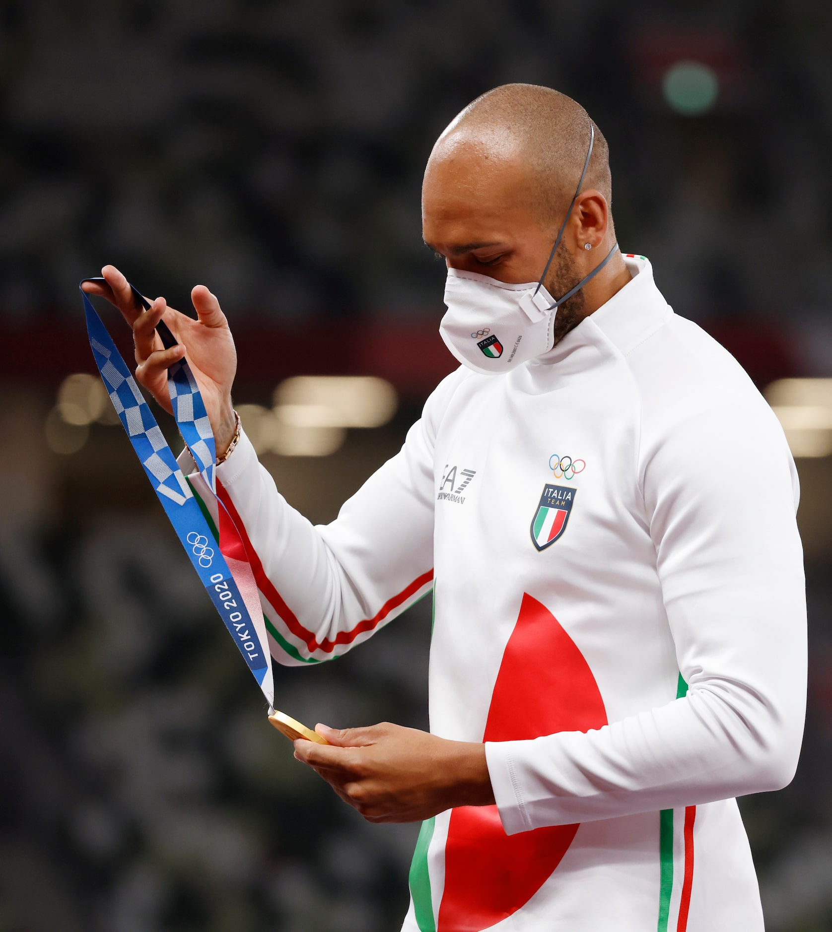 Italy’s Lamont Marcell Jacobs looks at his gold medal before putting it on as the winner of...