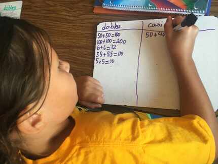 A second-grade student works to solve math problems during a lesson taught in Spanish. ...