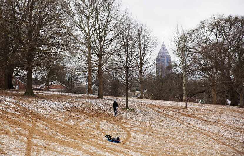  Children try to sled down a hill dusted in snow in Piedmont Park Saturday, Jan. 23, 2016,...