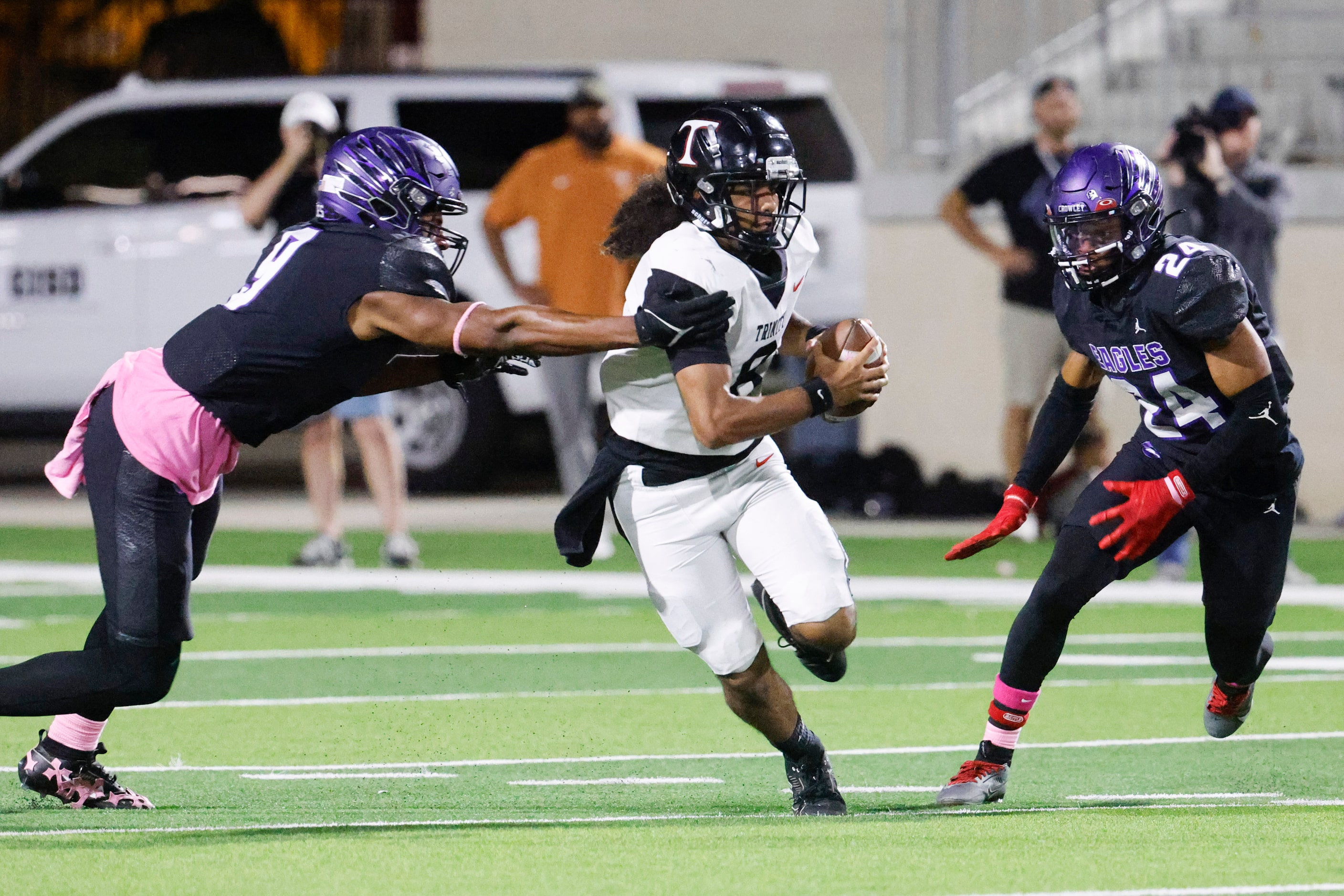 Trinity high school’s QB TJ Tupou (center) runs with the ball past Crowley high’s Priest...