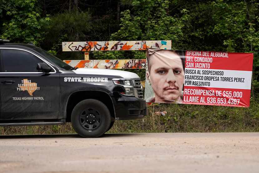 A Texas state trooper vehicle passes a posted wanted sign for a mass shooting suspect...