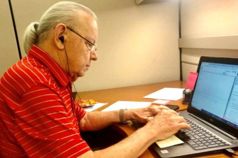 A Senior Source volunteer named Bob works at a laptop. He is wearing a red shirt with white...