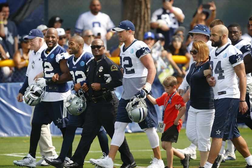 Dallas Police Chief David Brown, center, walks arm-in-arm with. from left, Dallas Cowboys...