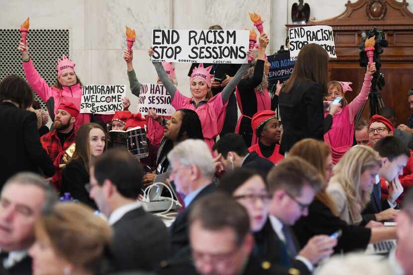 Code Pink demonstrators hold up signs before the start of Sen. Jeff Sessions' confirmation...