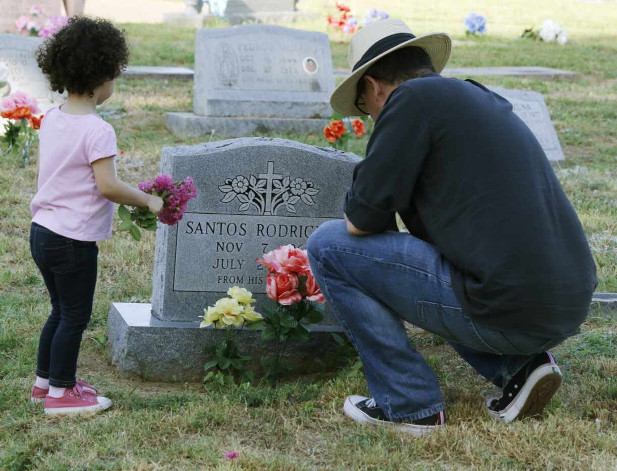 Roberto Corona, right,  and his daughter, Sophia, 2, places flowers at Oakland Cemetery on...