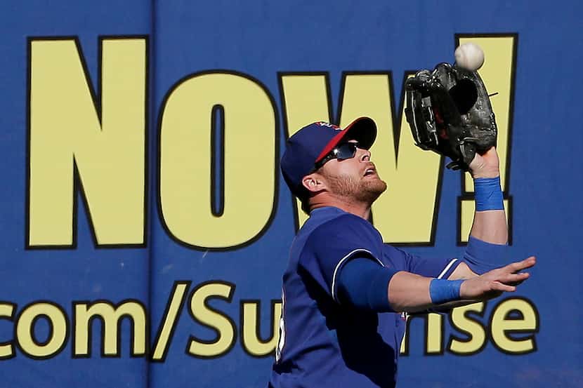 Texas Rangers center fielder Craig Gentry catches a fly ball during an exhibition spring...