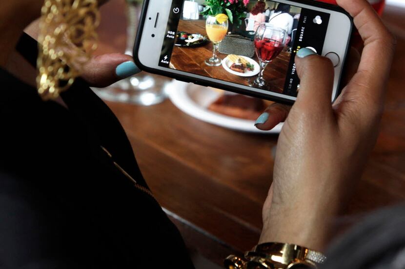 Angela West takes a picture for her Facebook page during Waffle Wars, a Savor Dallas event...
