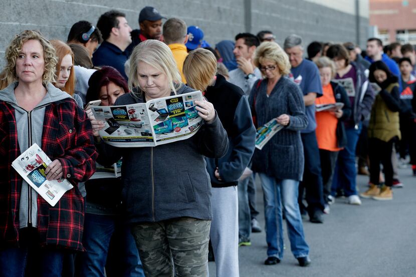 FILE - In this Nov. 23, 2017, file photo, people wait in line for a Best Buy store to open...