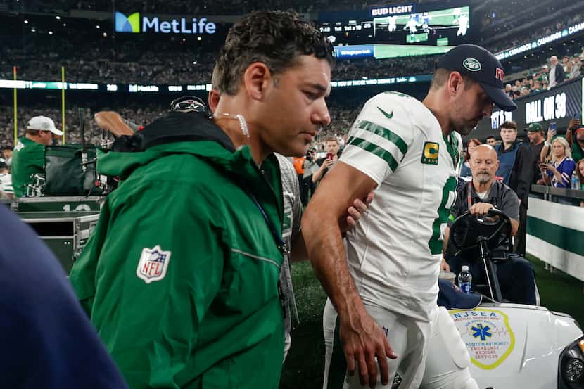 New York Jets quarterback Aaron Rodgers (8) is helped off the field during the first quarter...