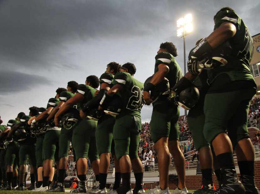 Members of the Mansfield Lake Ridge football team stand in unison during the playing of the...