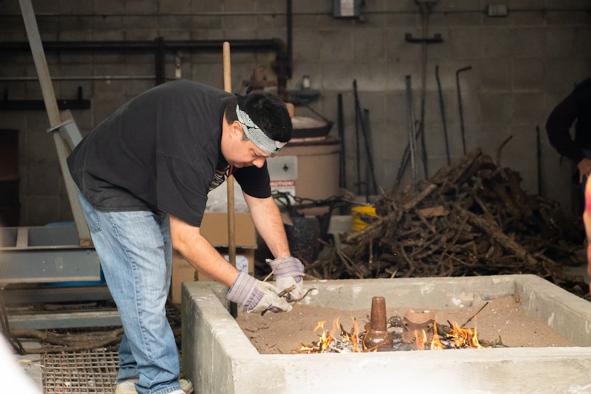 Chase Kahwinhut Earles tending to an open bonfire, which he uses to fire his ceramics, at a...