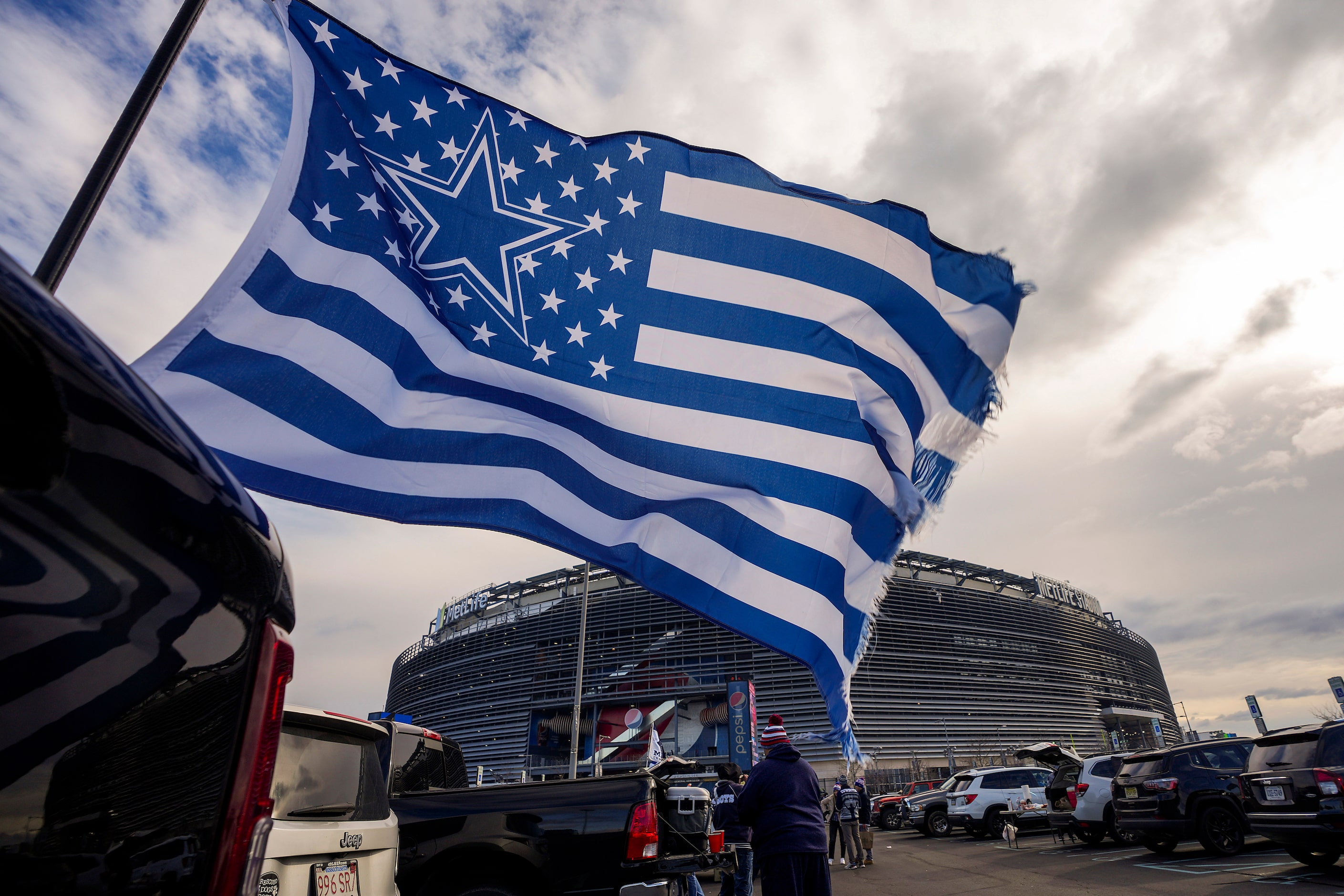 A Dallas Cowboys flag flutters in the wind as fans tailgate before an NFL football game...