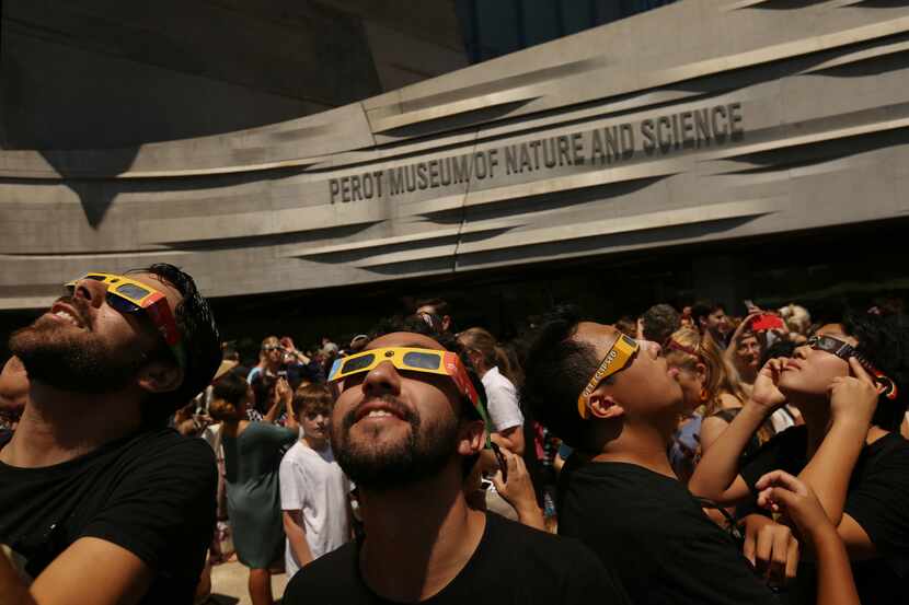 People watch the sun during a solar eclipse outdoor watch party at the Perot Museum of...
