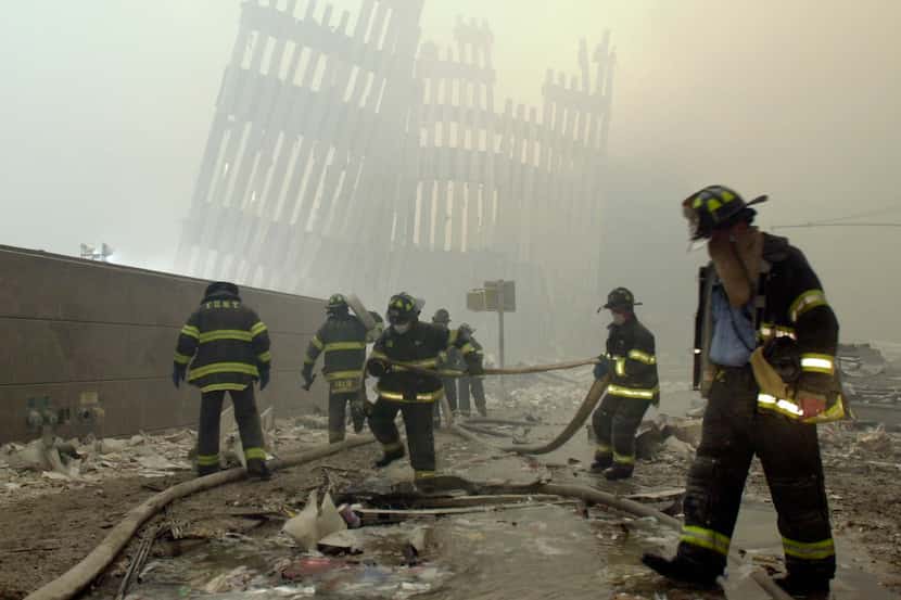 In this Sept. 11, 2001, photo, firefighters work beneath the destroyed vertical struts that...