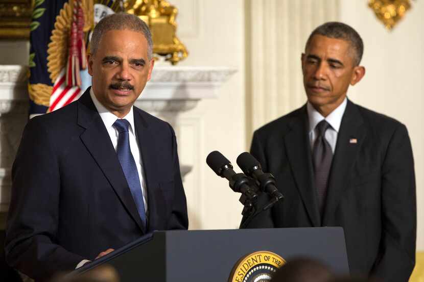 President Barack Obama (right) looked on as Attorney General Eric Holder spoke in the State...