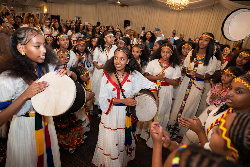 Niyat Daniel, left, and Dalia Meareg, center, slap at drums as they lead a group of female...