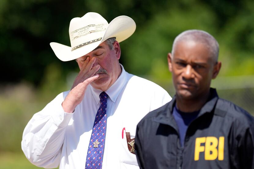 San Jacinto County Sheriff Greg Capers, left, wipes his eye as FBI Houston Special Agent in...