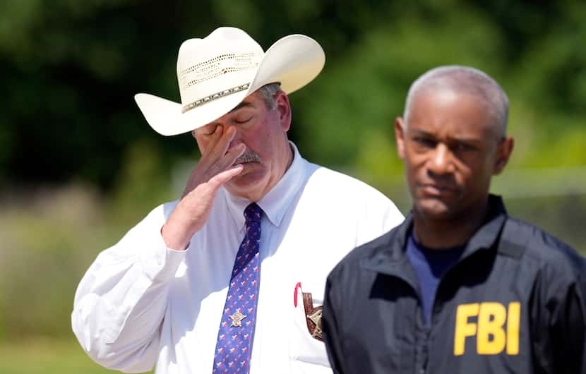San Jacinto County Sheriff Greg Capers, left, wipes his eye as FBI Houston Special Agent in...