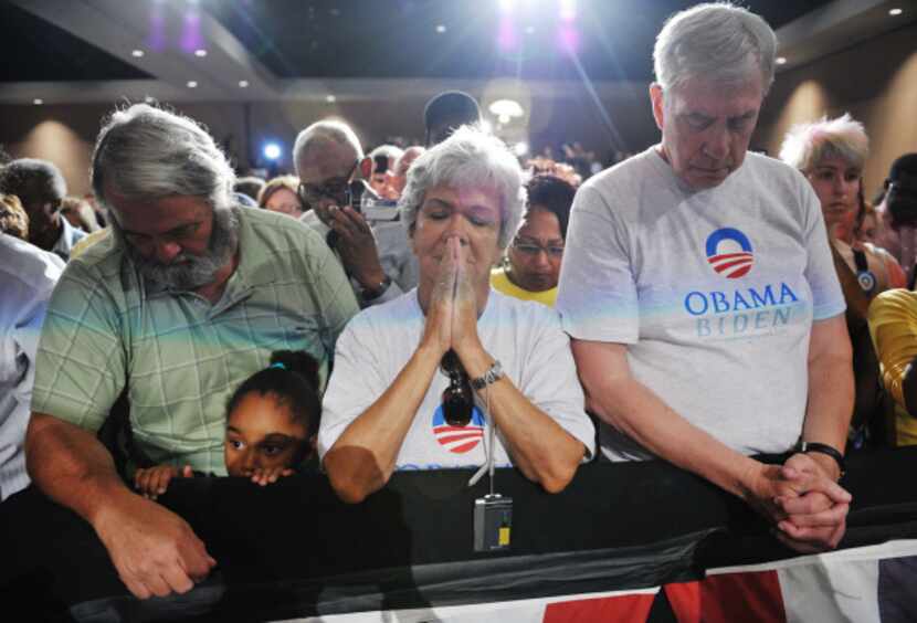 Obama supporters bow their heads during a moment of silence for the victims of the Aurora,...