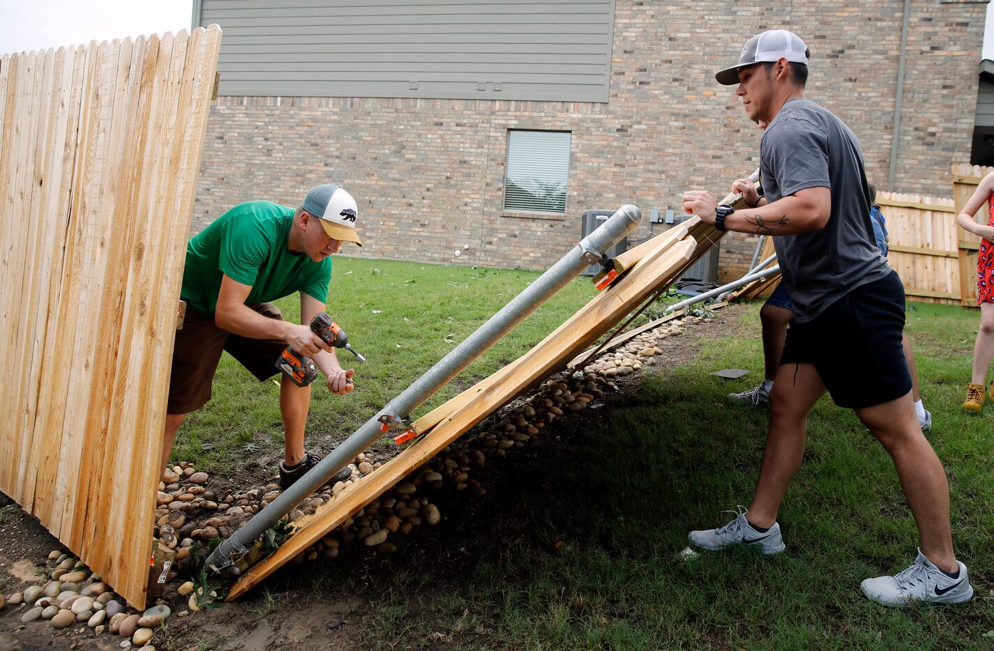 Neighbors, including Jon Lambrecht (left), help remove a downed fence on Oliver Drive in...