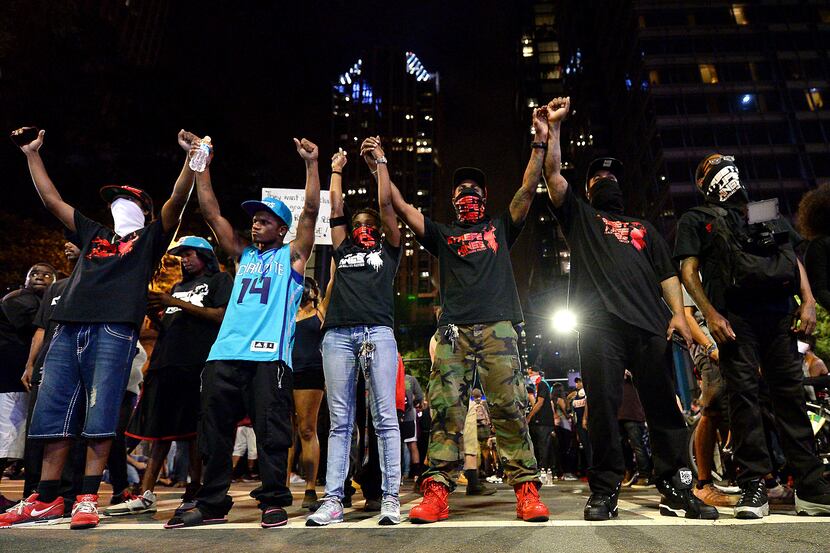 Protesters raise their arms in Charlotte, N.C. on Thursday. After two nights of violence, a...