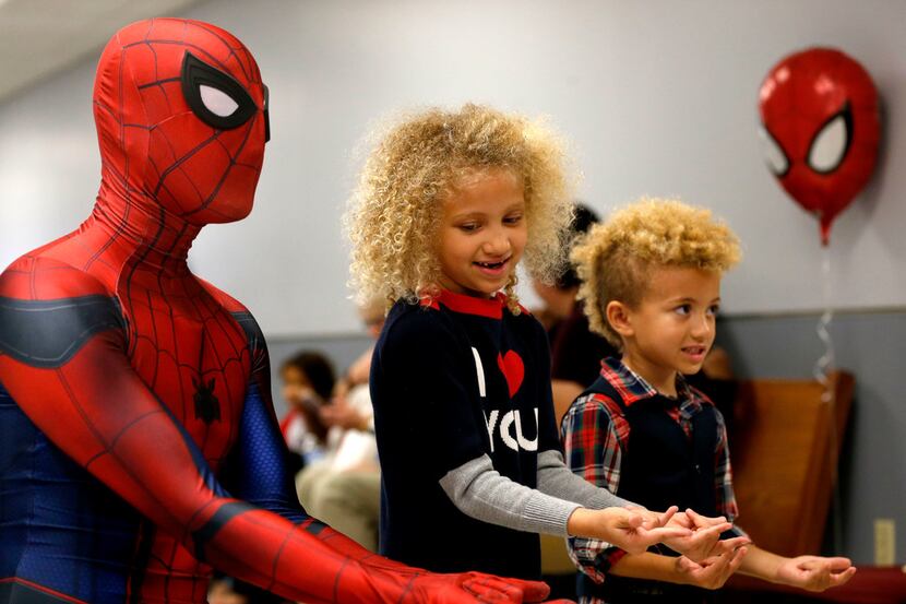 Chase Blackmore, dressed as Spiderman, poses for photos with adopted siblings Brett Sims...