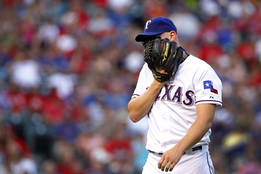 Texas Rangers starting pitcher Matt Harrison (54) covers his face as he heads to the dugout...