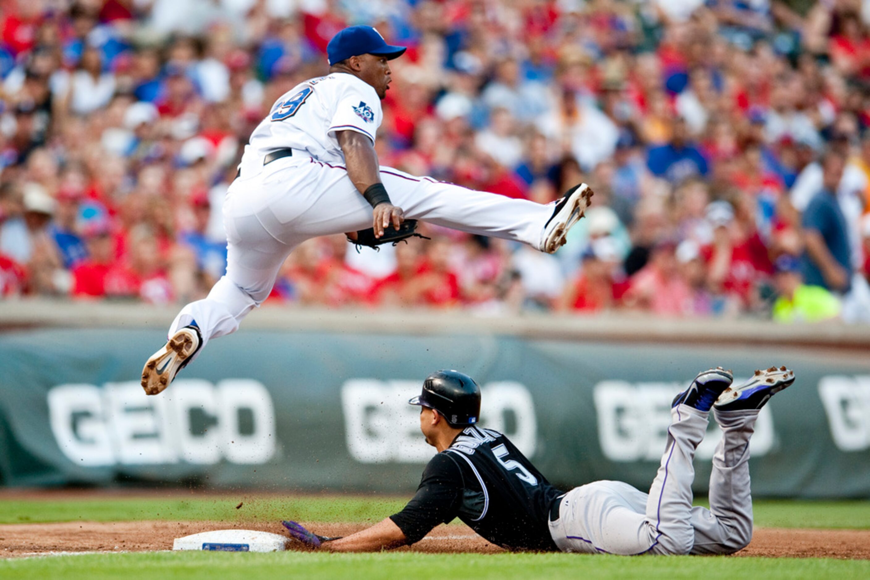 Texas Rangers third baseman Adrian Beltre leaps over Colorado Rockies left fielder Carlos...