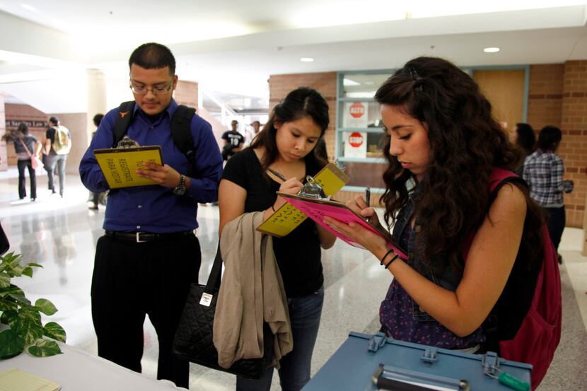 Left to right, Students Roger Camacho, Jennifer Chantaca, and Amairani Ayala fill out voter...