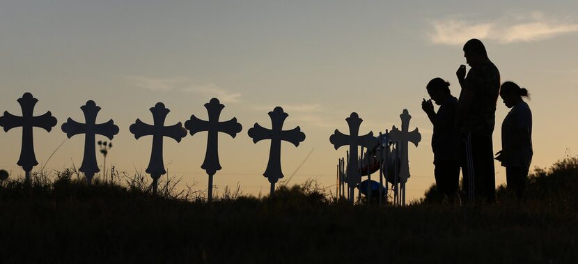 Irene and Kenneth Hernandez and their daughter Miranda Hernandez say a prayer in front of...