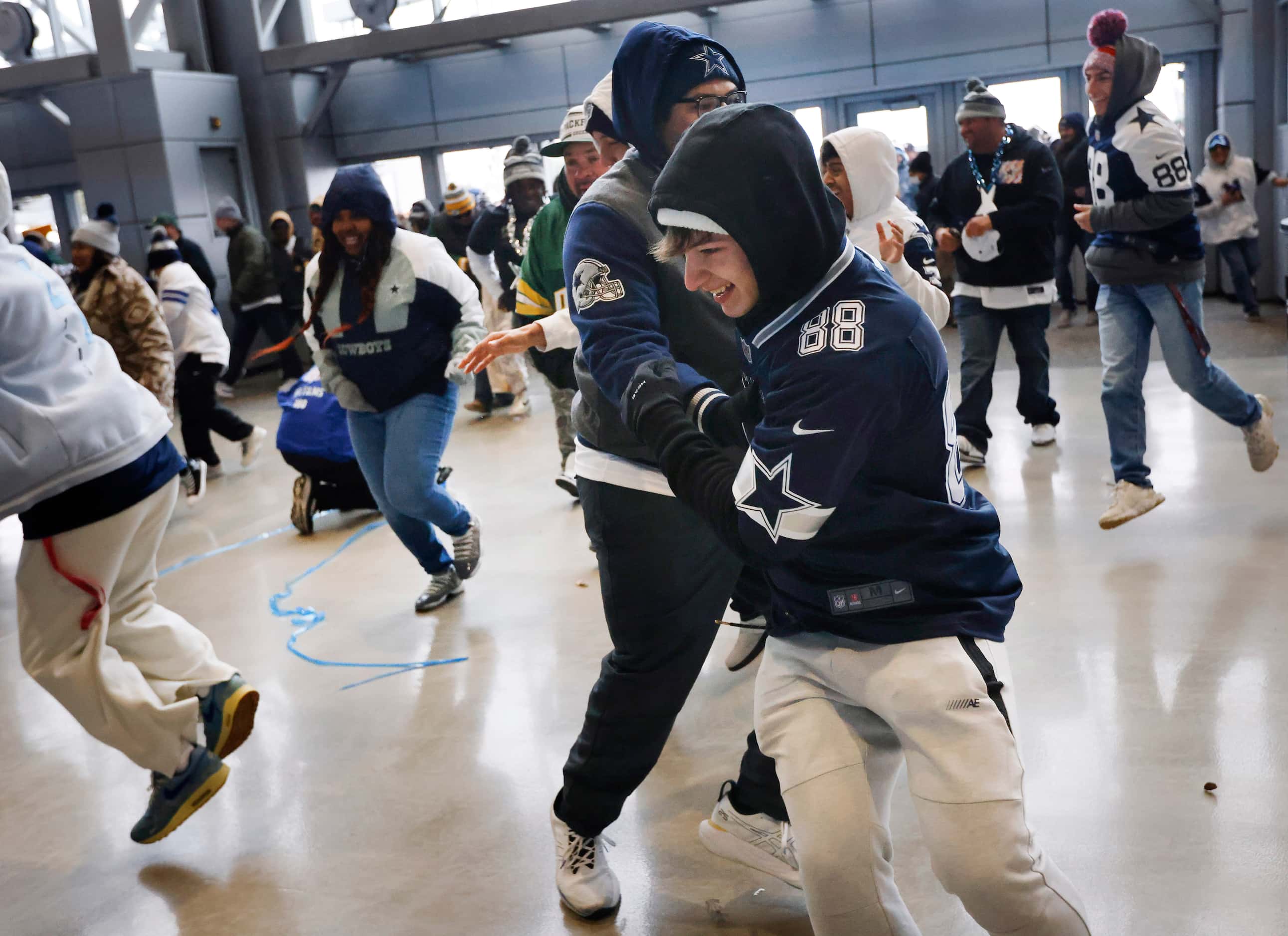A pair of Dallas Cowboys fans collide as they race through the west plaza doors in hopes of...