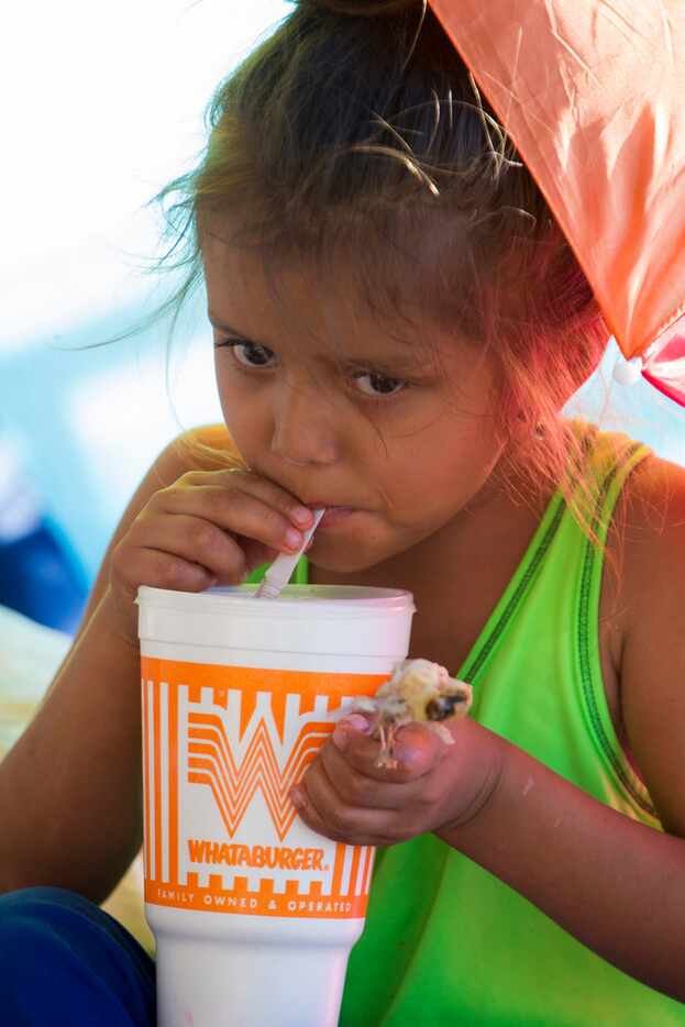 Michelle, 6, drinks from a Whataburger cup on the U.S. side of the Hidalgo bridge in between...