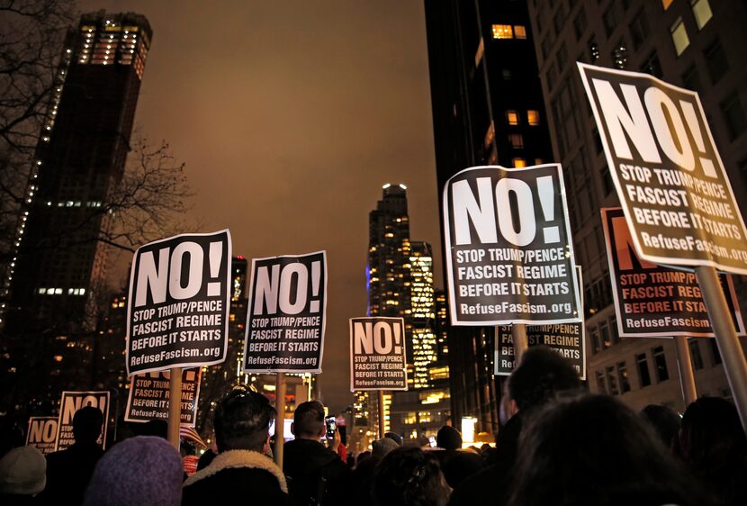 Protesters hold signs as they listen to speakers at an anti-Trump rally hosted by filmmaker...