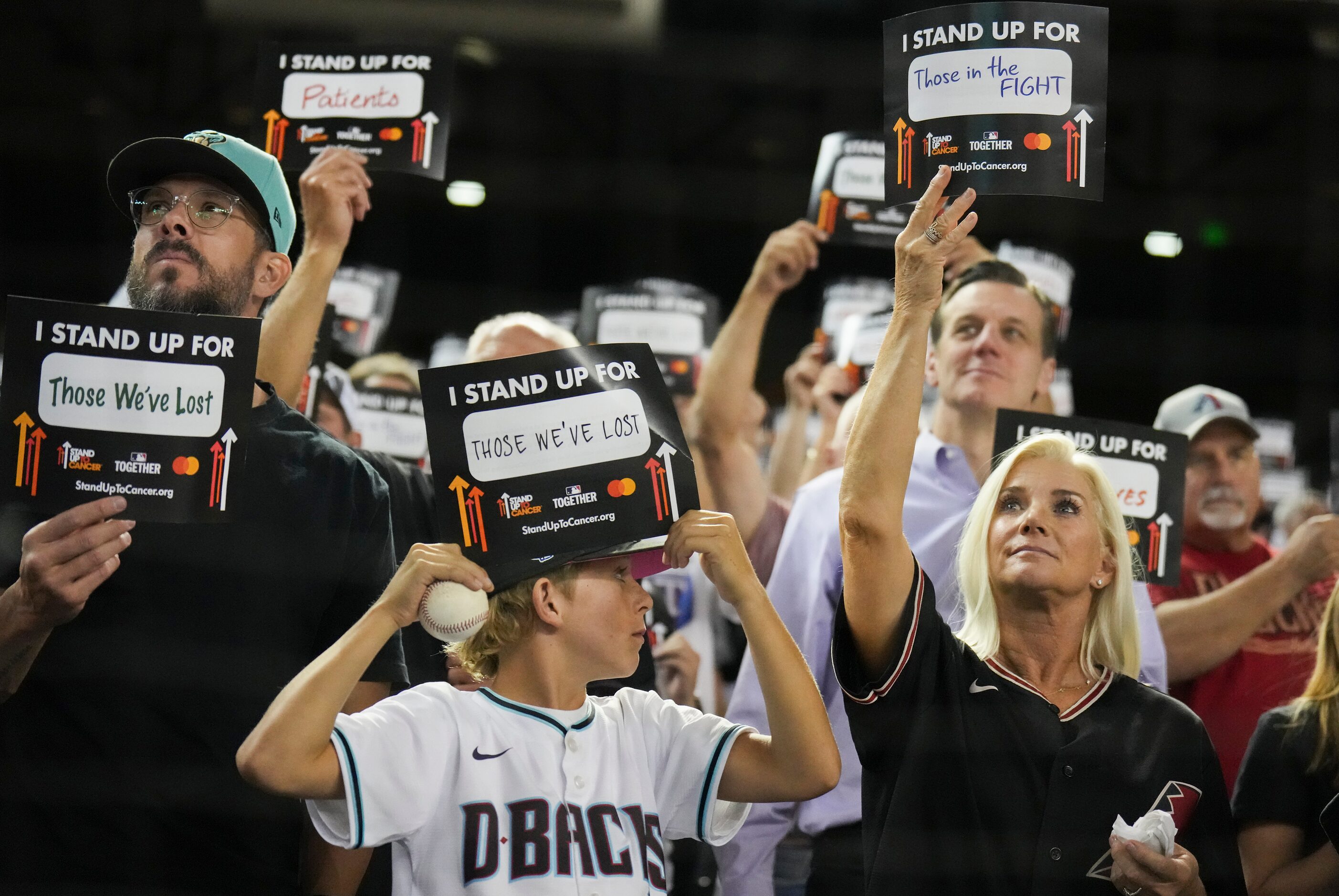 Fans hold up Stand Up to Cancer signs after the fifth inning in Game 4 of the World Series...