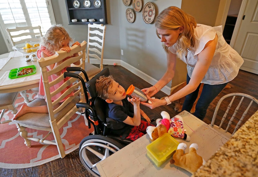 Kasey Woleben, right, held a cup for son Will as daughter Lauren looked on at their home in...