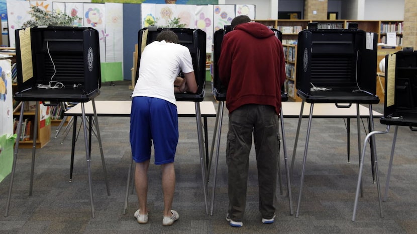 Austin Rivard, 18, left, votes next to his father, Dana Rivard at Sherrod Elementary School...