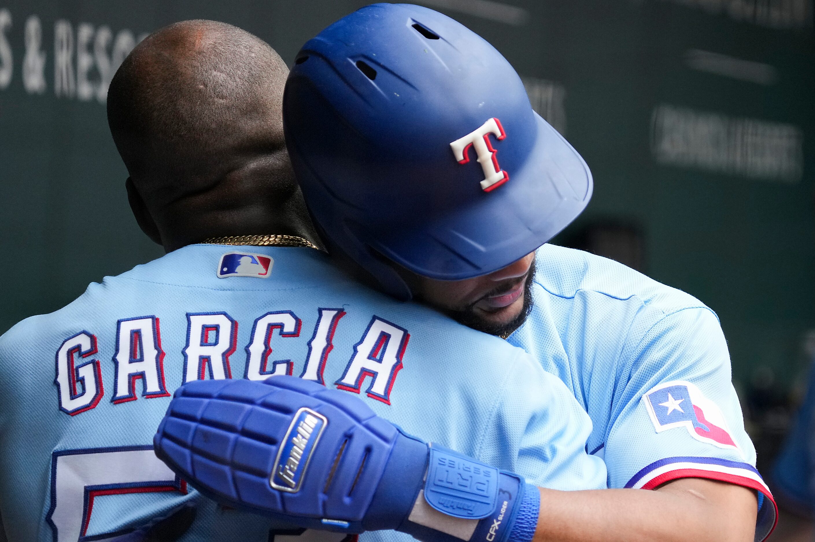 Texas Rangers center fielder Leody Taveras hugs right fielder Adolis Garcia in the dugout...