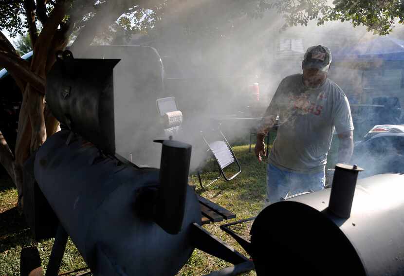 Stacey Walker of Dallas tends to the pit at a friend's house near Fair Park on Saturday,...