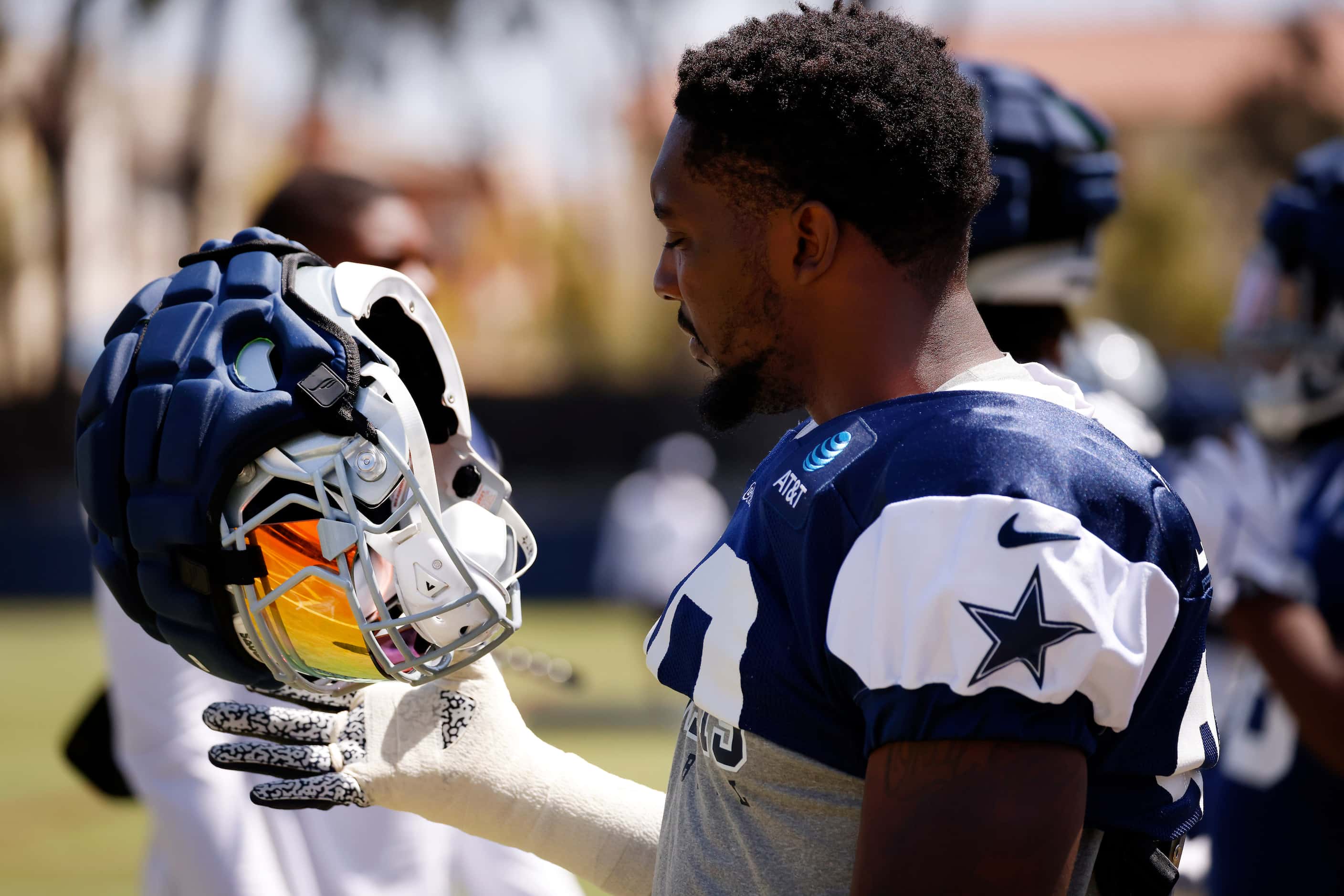 Dallas Cowboys defensive end DeMarcus Lawrence (90) flips his helmet as he prepares for the...