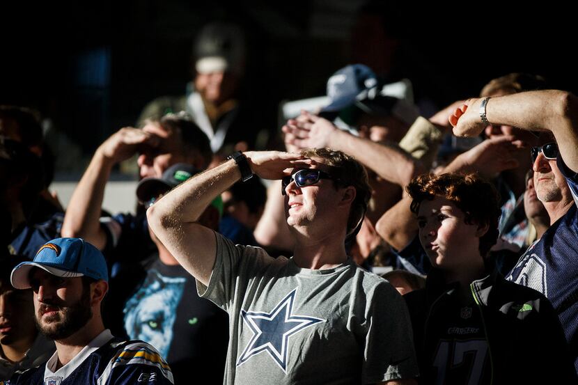 Dallas Cowboys fans shield their eyes from the sun entering the stadium during the first...
