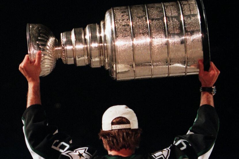 Stars player Mike Modano hoists the Stanley Cup over his head during a ceremony at Reunion...