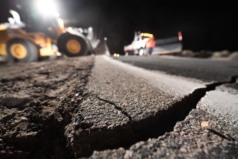 Highway workers repair a hole that opened in the road as a result of the July 5, 2019...