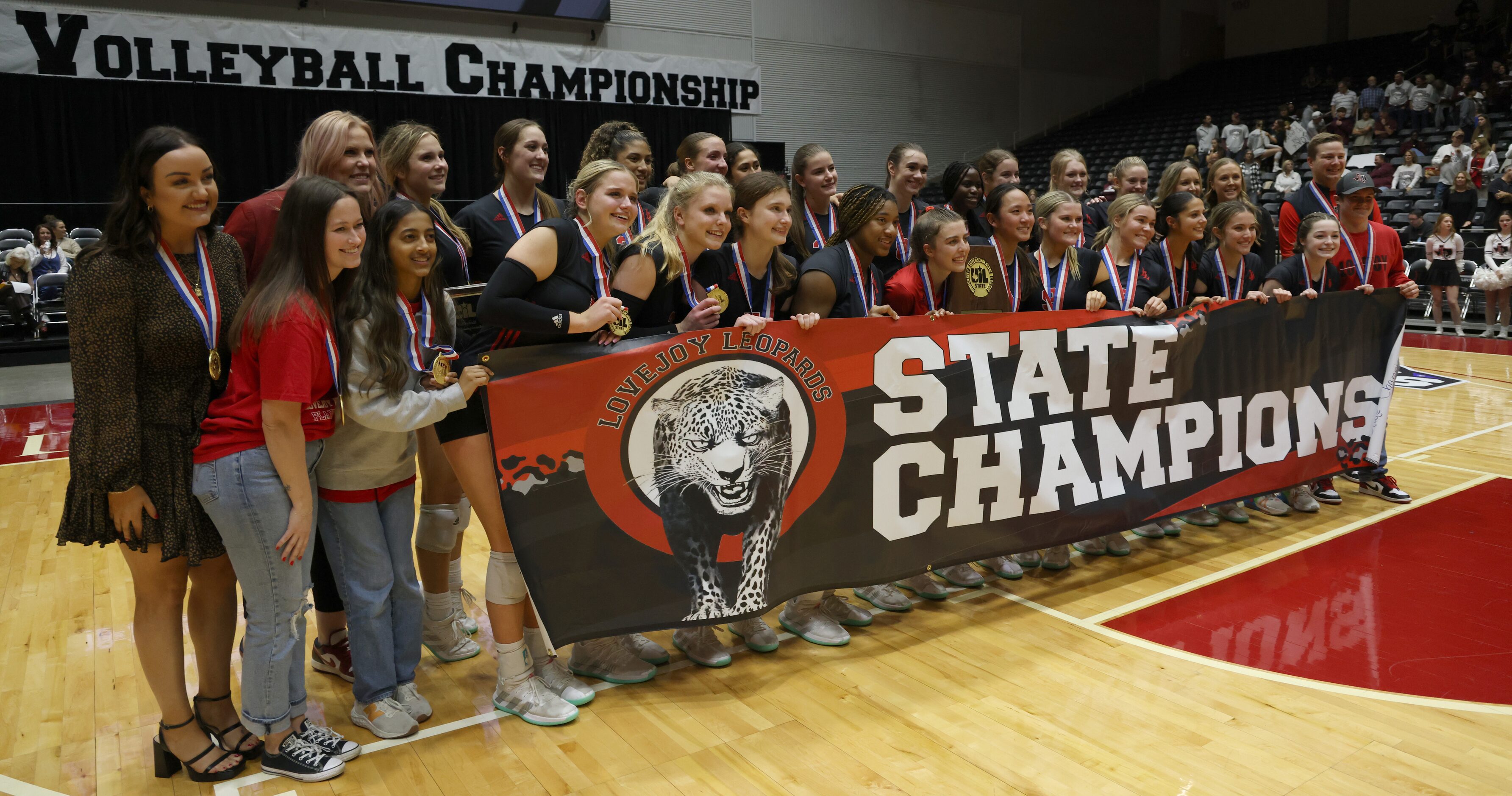 Lucas Lovejoy players and staff members pose for a photo with a banner and trophy following...