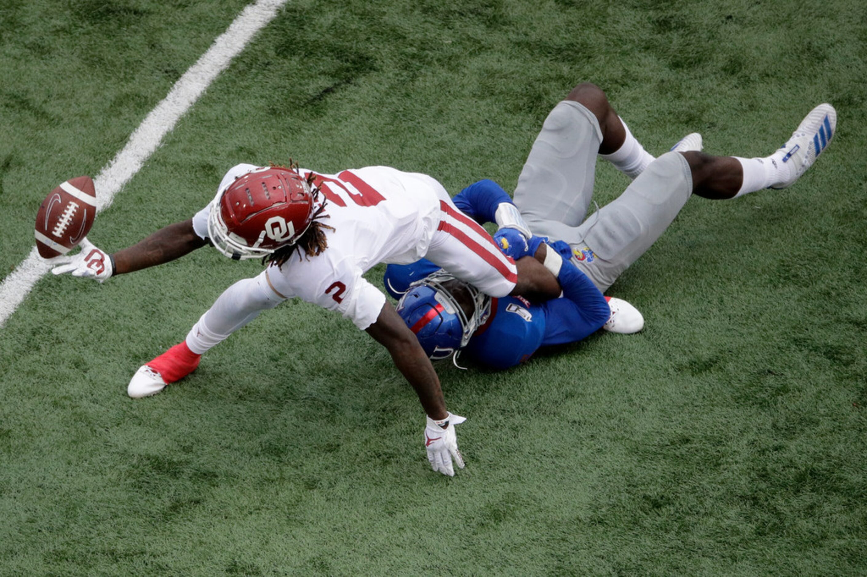 Kansas linebacker Azur Kamara (5) tackles Oklahoma wide receiver CeeDee Lamb (2) as he...