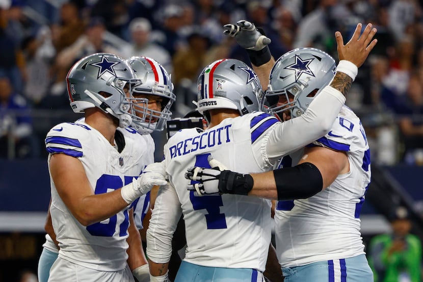 Dallas Cowboys quarterback Dak Prescott (4) is congratulated by teammates after rushing for...