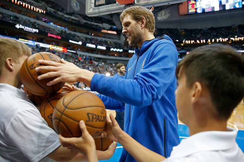 Dallas Mavericks center Dirk Nowitzki takes balls from a ball boy during the warm-up before...