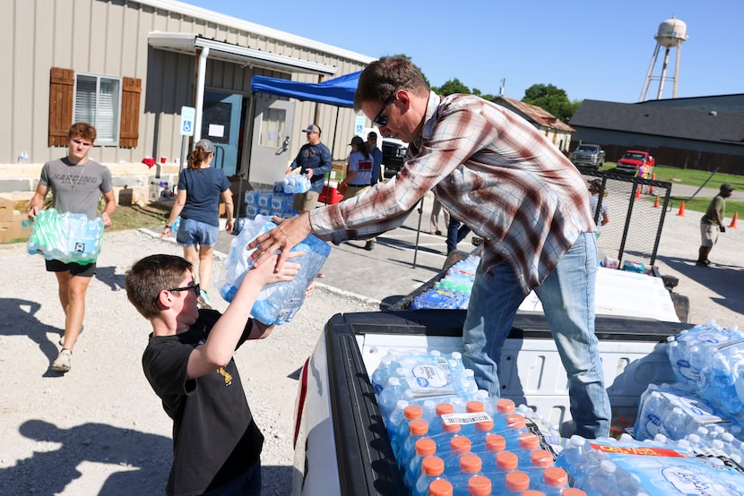 Volunteer Travis Purcell (right) loads a truck with water for donations for the tornado...