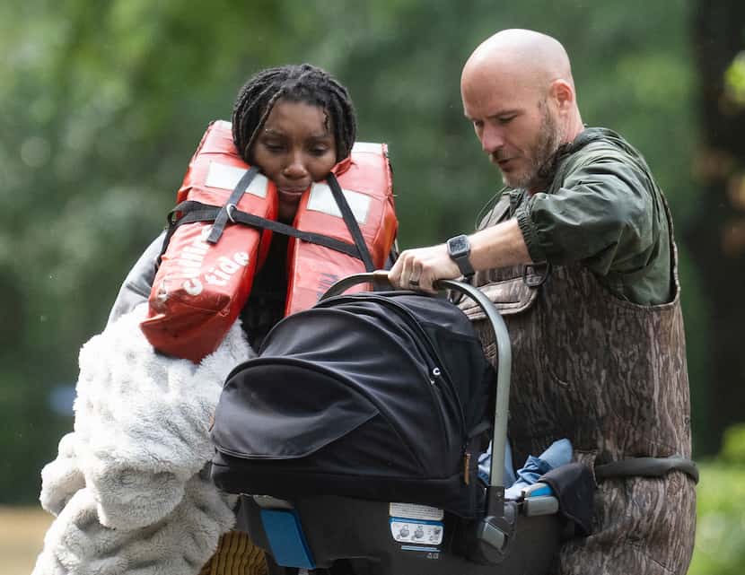 A woman is handed her child after being evacuated by boat from her homes with the help of...