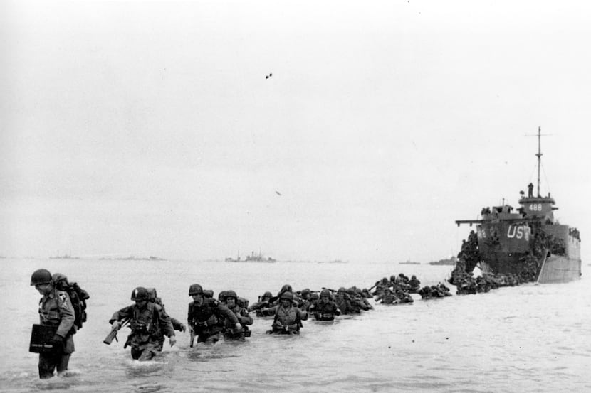 U.S. reinforcements wade through the surf from a landing craft in the days following D-Day...
