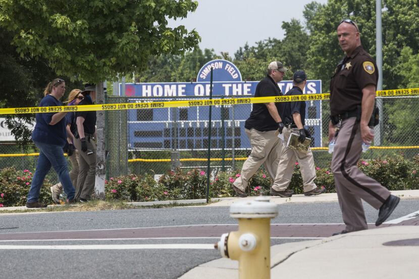 Law enforcement officials work near Eugene Simpson Field, the site where a gunman opened...